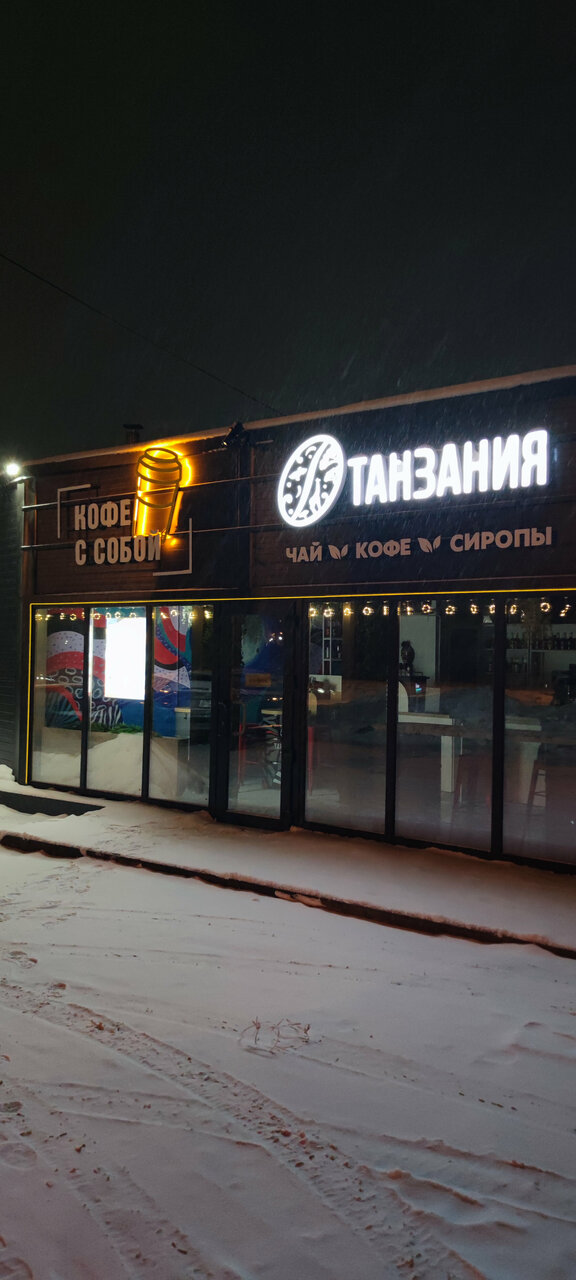 Кофейня «Танзания» ночью: подсвеченная золотом вывеска на чёрном фасаде и снег